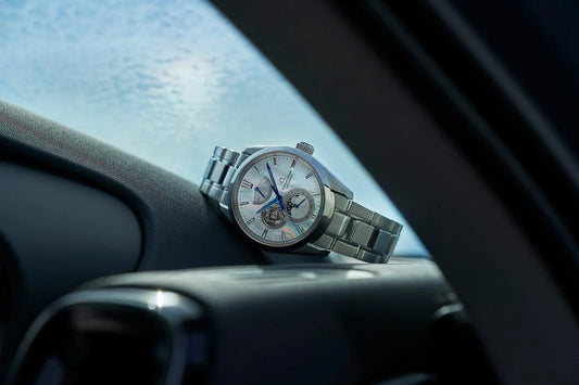 車内ダッシュボードに置かれた高級感のある機械式腕時計、シルバーメタルブレスレット、オープンハートデザイン