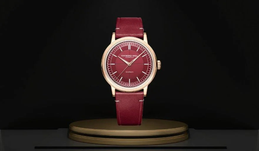 Elegant burgundy leather wristwatch with gold case and red dial on display pedestal