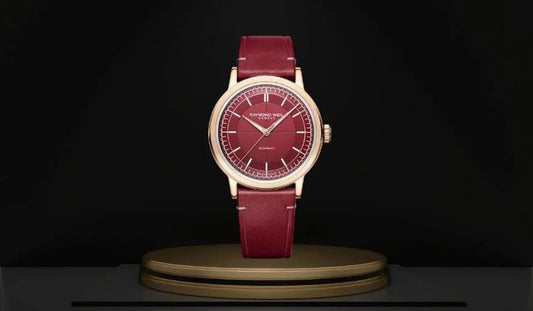 Elegant burgundy leather wristwatch with gold case and red dial on display pedestal