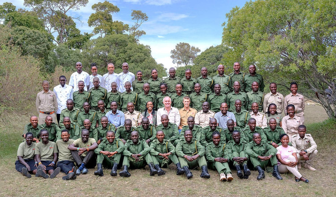CONTÉVANOU, large group photo of safari guides and staff in green and beige uniforms outdoors