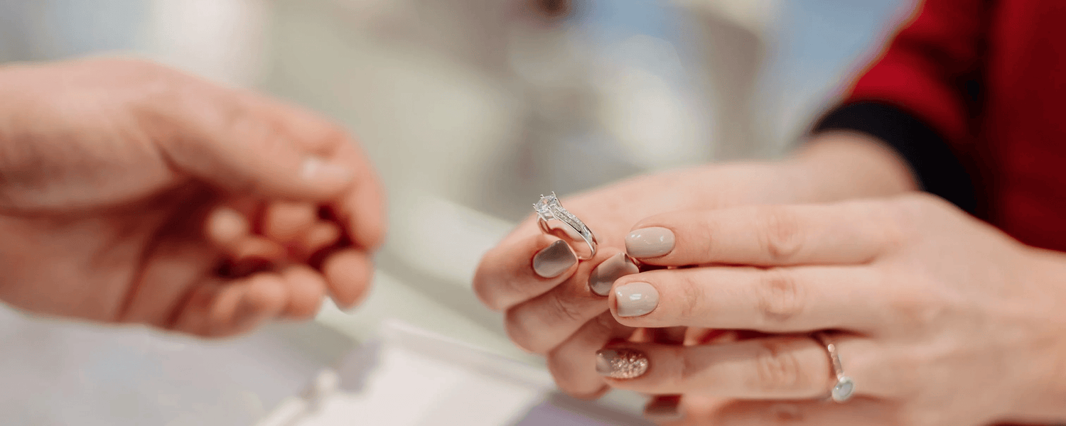Hands exchanging a diamond ring in a jewelry store, focus on elegant engagement ring