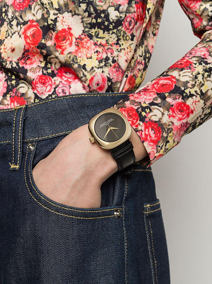 黒革ベルトのゴールド腕時計を着用した花柄シャツとデニムのコーディネート