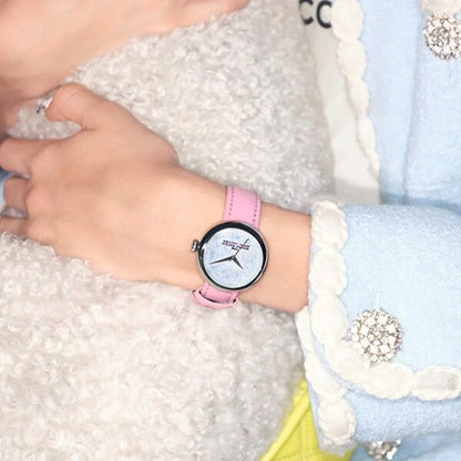 ピンクのレザーストラップ腕時計、パール調文字盤、女性の手元コーデ