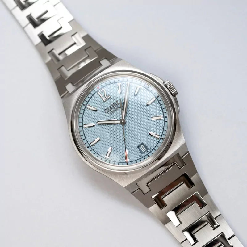氷河ブルーの文字盤と独特なメタルブレスレットが特徴の高級腕時計、日付表示付き