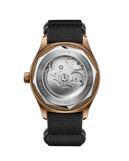 ブロンズケースと黒いナイロンストラップの機械式腕時計、シースルーバックでムーブメントが見える